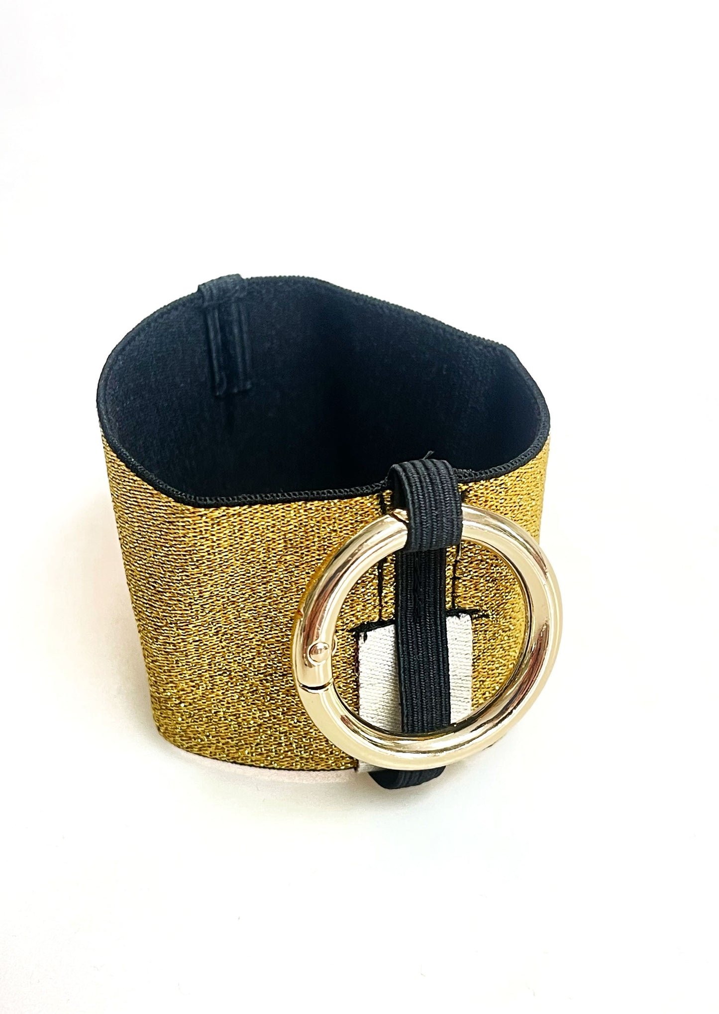 Ein Becherhalter aus einem gold glitzernden, breiten Gummiband, innen schwarz, mit einem runden, goldenen Karabinerhaken. Das Gummiband ist zu einem Kreis zusammengenäht. Der Karabiner ist an einem Schmalen Gummiband befestigt, das unten um das breite Gummiband herum geht.