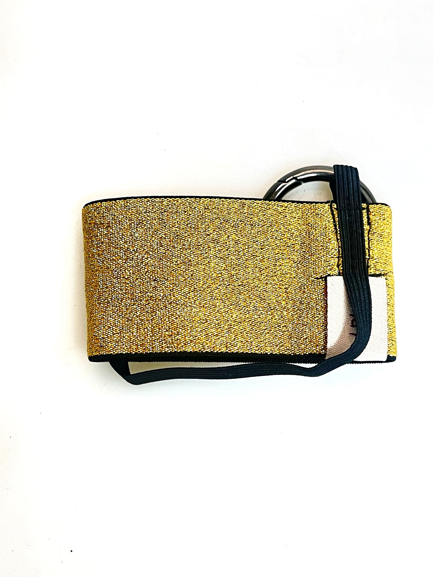 Der goldene Becherhalter flach hingelegt. Man sieht, dass das schmale, schwarze Gummiband unten um den Halter herum geht.