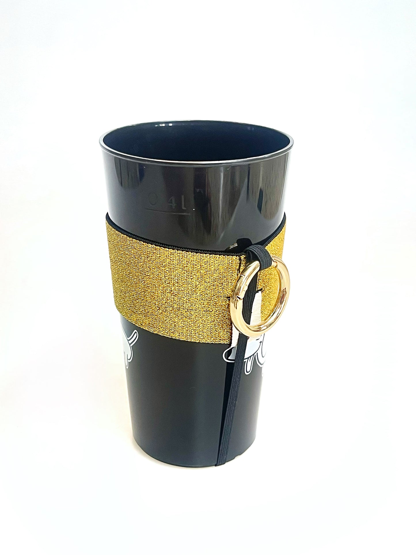 Ein Becher steckt im goldenen Becherhalter. Das schwarze, schmale Gummiband geht unten um den Becherboden herum.