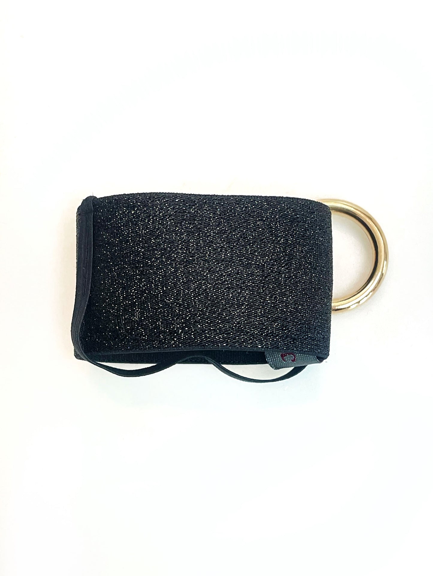Der schwarze Becherhalter flach hingelegt. Man sieht, dass das schmale, schwarze Gummiband unten um den Halter herum geht.