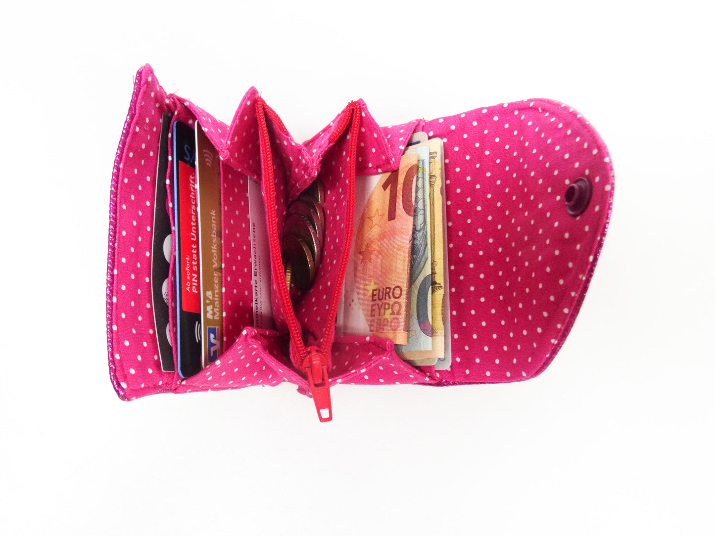 die pinke Geldbörse aufgeklappt und gefüllt mit Karten, Gelkdscheinen und Kleingeld.