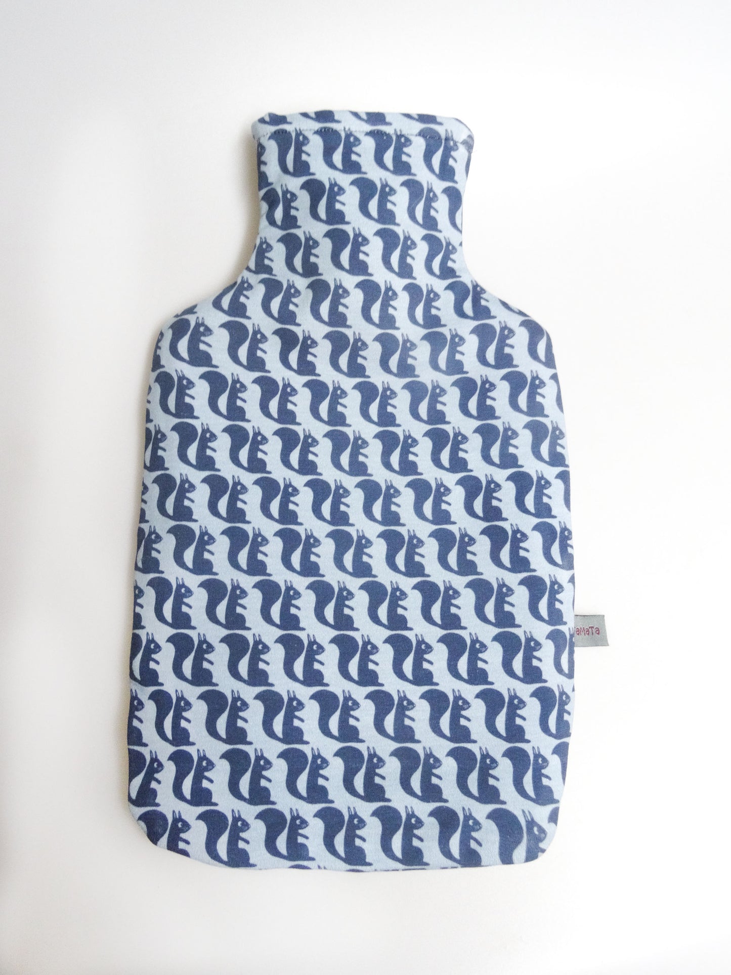 Das Vorderteil der Wärmflasche mit den blauen, gezeichneten Eichhörnchen senkrecht von oben fotografiert.