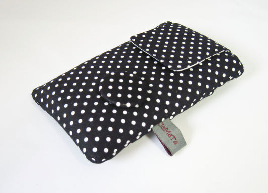 Eine Handytasche aus schwarzer Baumwolle mit weißem Pünktchen. Die Tasche hat eine Klappe zum Verschließen und unten rechts einen Button aus dem Pünktchenstoff. 
Aufnahme seitlich von unten.