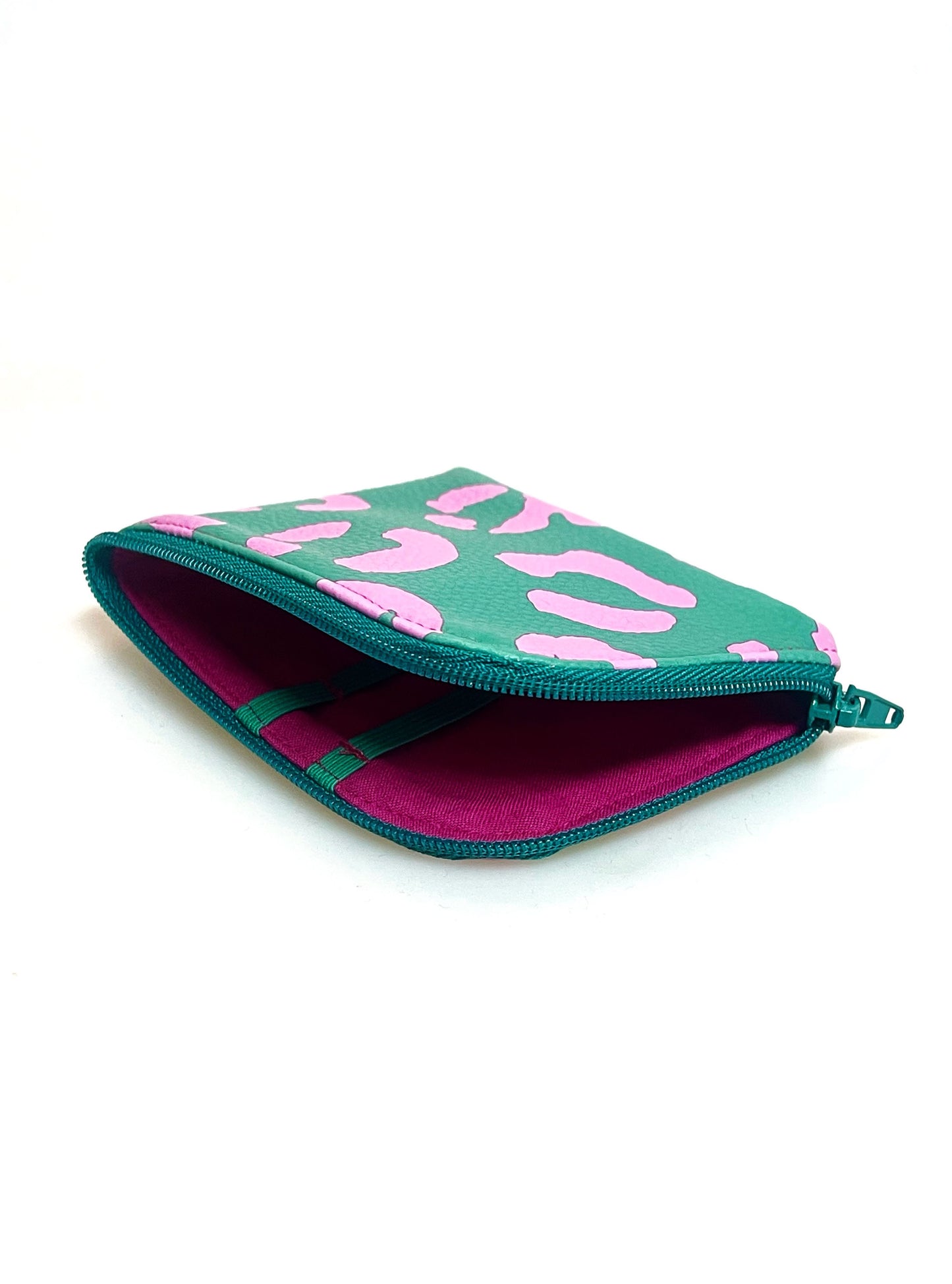 Kleine Geldbörse aus grünem Kunstleder mit pinken Leopradenflecken. Sie ist rechteckig mit einer abgerundeten Ecke. An zwei Seiten ist sie mit einem grünen Reißverschluss geschlossen. Ansicht mit offenem Reißverschluss. Man sieht das pinke Futter und die grünen Gummibänder.  
