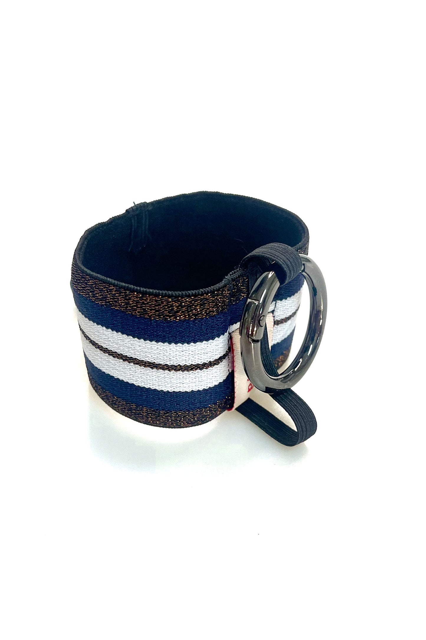 Ein Becherhalter aus einem breiten Gummiband mit Streifenmuster in weiß, dunkelblau und kupfer mit schwarz-Glitzer. Er hat einem runden, gunmetal farbenen Karabinerhaken. Das Gummiband ist zu einem Kreis zusammengenäht. Der Karabiner ist an einem schmalen Gummiband befestigt, das unten um das breite Gummiband herum geht. 