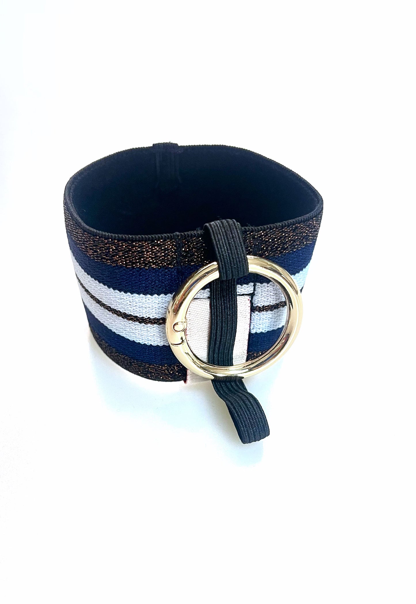 Ein Becherhalter aus einem breiten Gummiband mit Streifenmuster in weiß, dunkelblau und kupfer mit schwarz-Glitzer. Er hat einem runden, goldenen Karabinerhaken. Das Gummiband ist zu einem Kreis zusammengenäht. Der Karabiner ist an einem schmalen Gummiband befestigt, das unten um das breite Gummiband herum geht. 