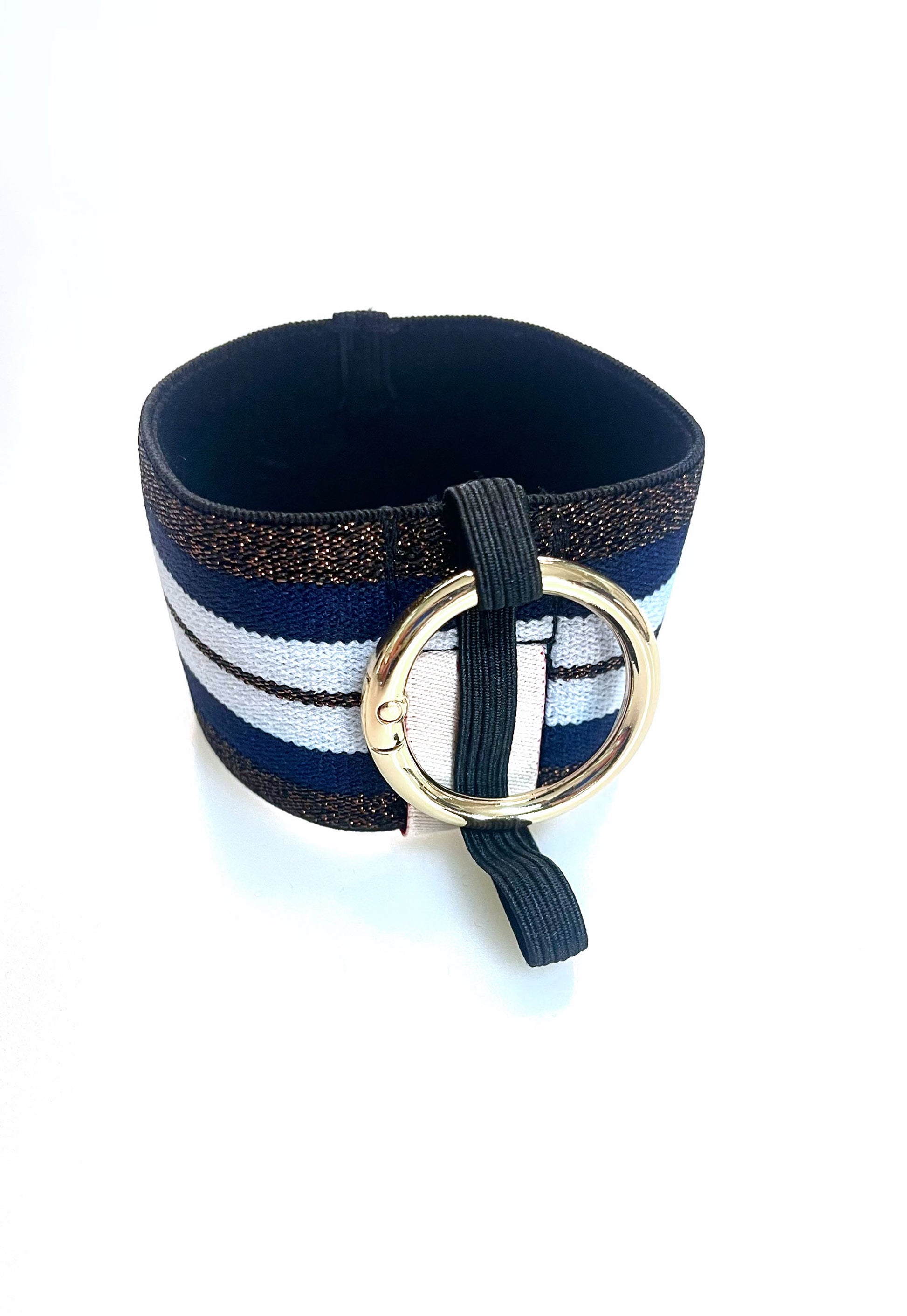 Ein Becherhalter aus einem breiten Gummiband mit Streifenmuster in weiß, dunkelblau und kupfer mit schwarz-Glitzer. Er hat einem runden, goldenen Karabinerhaken. Das Gummiband ist zu einem Kreis zusammengenäht. Der Karabiner ist an einem schmalen Gummiband befestigt, das unten um das breite Gummiband herum geht. 